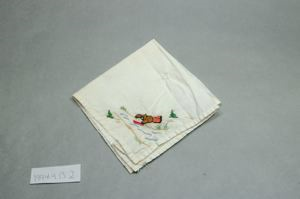 Image of Figure with miniature boat, one of a set of 2 embroidered napkins with scenes of Inuit figure at play